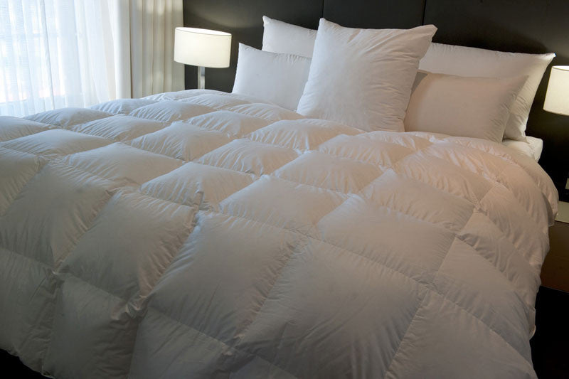 White boxed baffle quilt on a made bed with matching white pillows and bedside lamps