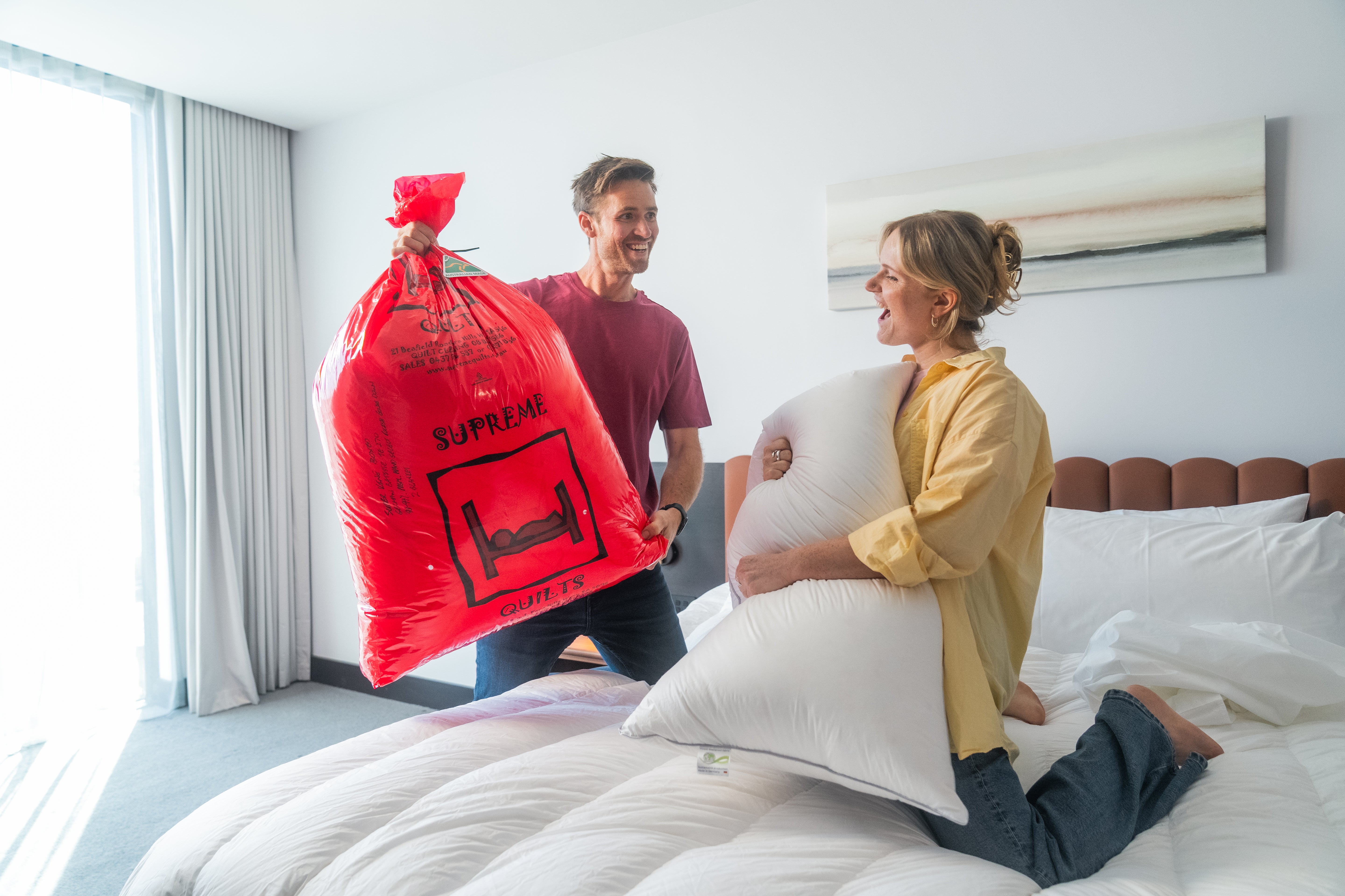 Supreme Quilts white down quilt displayed in a modern bedroom setting, being unpacked from its signature red packaging, showcasing its premium loft, softness & warmth.